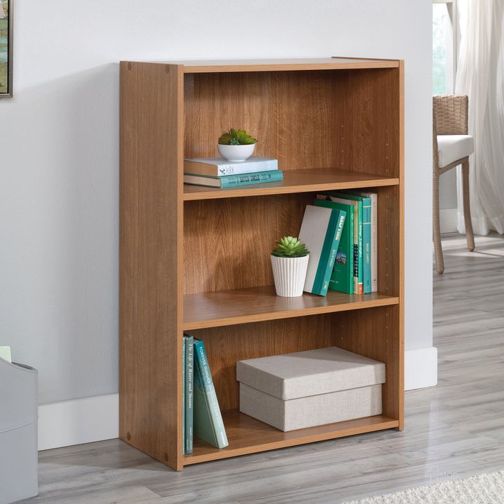 The appearance of Beginnings 3-Shelf Bookcase In Highland Oak designed by Sauder in the transitional interior design. This highland oak piece of furniture  was selected by 1StopBedrooms from Beginnings Collection to add a touch of cosiness and style into your home. Sku: 413322. Product Type: Bookcase. Material: Engineered Wood. Image1