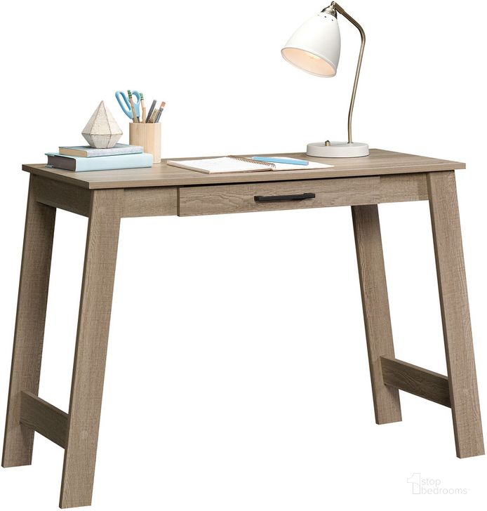 The appearance of Beginnings Writing Table In Summer Oak designed by Sauder in the transitional interior design. This summer oak piece of furniture  was selected by 1StopBedrooms from Beginnings Collection to add a touch of cosiness and style into your home. Sku: 424259. Product Type: Writing Desk. Material: Engineered Wood. Image1