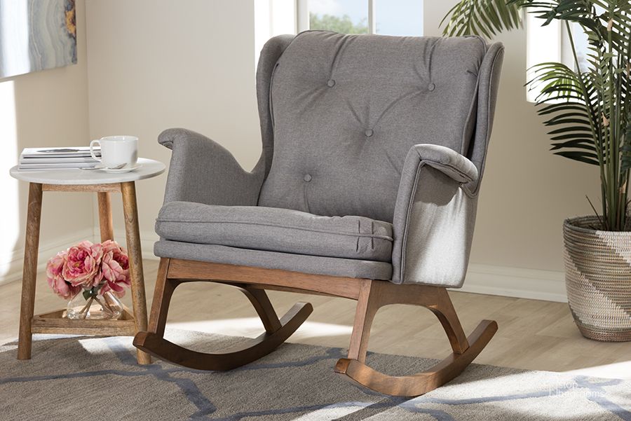 The appearance of Baxton Studio Maggie Mid-Century Modern Grey Fabric Upholstered Walnut-Finished Rocking Chair designed by Baxton Studio in the transitional interior design. This grey piece of furniture  was selected by 1StopBedrooms from Maggie Collection to add a touch of cosiness and style into your home. Sku: BBT5309-Grey-RC. Material: Fabric. Product Type: Living Room Chair. Image1