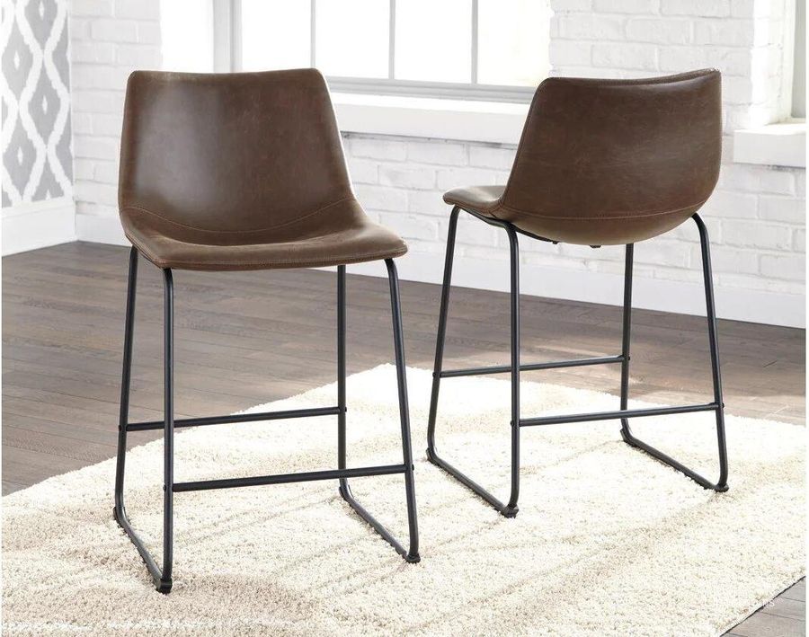 The appearance of Bren Brown Barstool Set of 2 0qd2299005 designed by Isaac Tahari in the modern / contemporary interior design. This brown piece of furniture  was selected by 1StopBedrooms from Bren Collection to add a touch of cosiness and style into your home. Sku: D372-124. Material: Leather Match. Product Type: Barstool. Image1