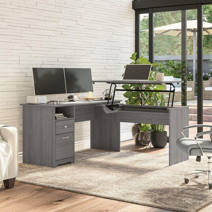 The appearance of Bush Furniture Cabot 60W 3 Position Sit To Stand L Shaped Desk in Modern Gray designed by Bush Furniture in the modern / contemporary interior design. This gray piece of furniture  was selected by 1StopBedrooms from Cabot Collection to add a touch of cosiness and style into your home. Sku: CAB043MG. Material: Wood. Product Type: Desk. Image1