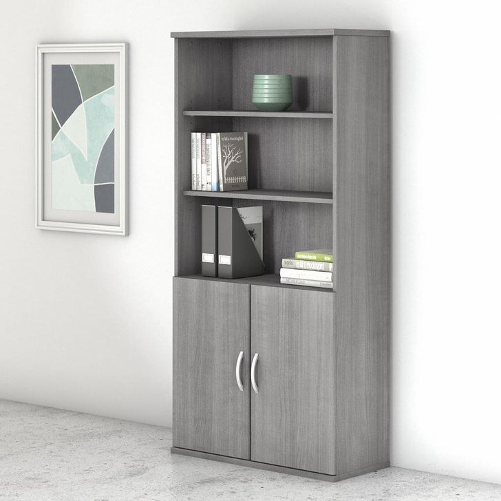 The appearance of Bush Business Furniture Studio C 5 Shelf Bookcase with Doors in Platinum Gray designed by Bush Furniture in the transitional interior design. This gray piece of furniture  was selected by 1StopBedrooms from Studio C Collection to add a touch of cosiness and style into your home. Sku: STC015PG. Product Type: Bookcase. Image1