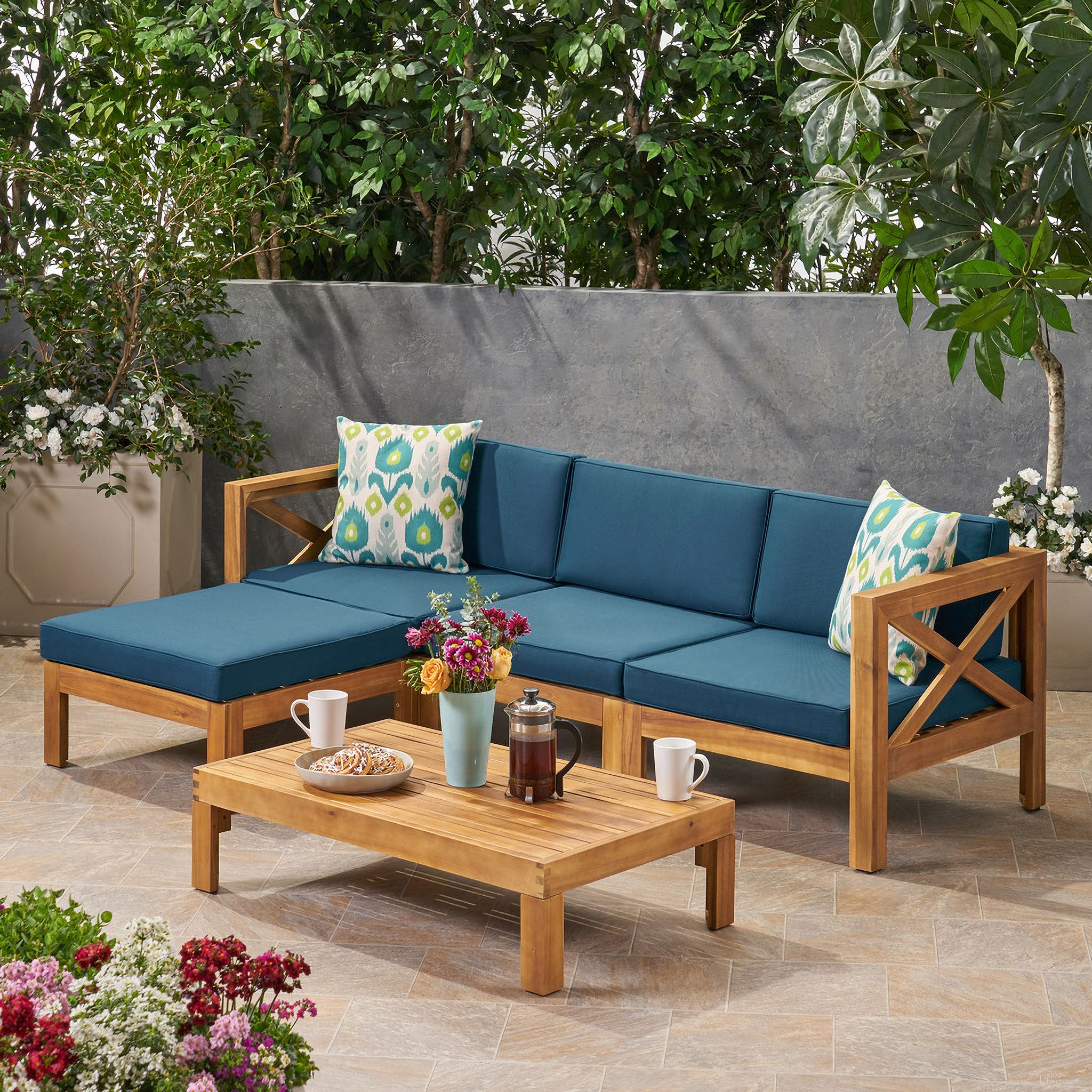 The appearance of Radiat 5-Piece Outdoor L-Shaped Sofa Set with Coffee Table and Water Resistant Cushions In Dark Blue and Teak designed by Noble House in the modern / contemporary interior design. This dark blue piece of furniture was selected by 1StopBedrooms from Radiat Collection to add a touch of cosiness and style into your home. Sku: 63714.00DT. Material: Acacia Wood.